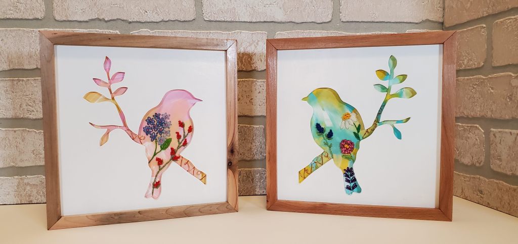 Two bird silhouettes, one pink background, one blue background. Embroidered floral designs on the inside.