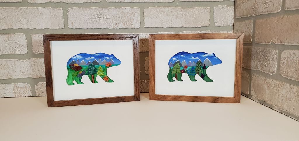 Two bear side profile silhouettes with a mountain scene background and embroidered floral designs