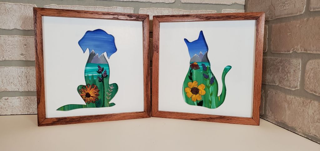 Dog and Cat sitting silhouette. Mountain and lake scene background with embroidered flower details.