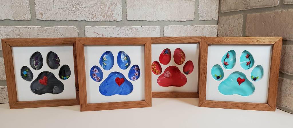 Dog paw print silhouette with black background, embroidered heart and flower details.