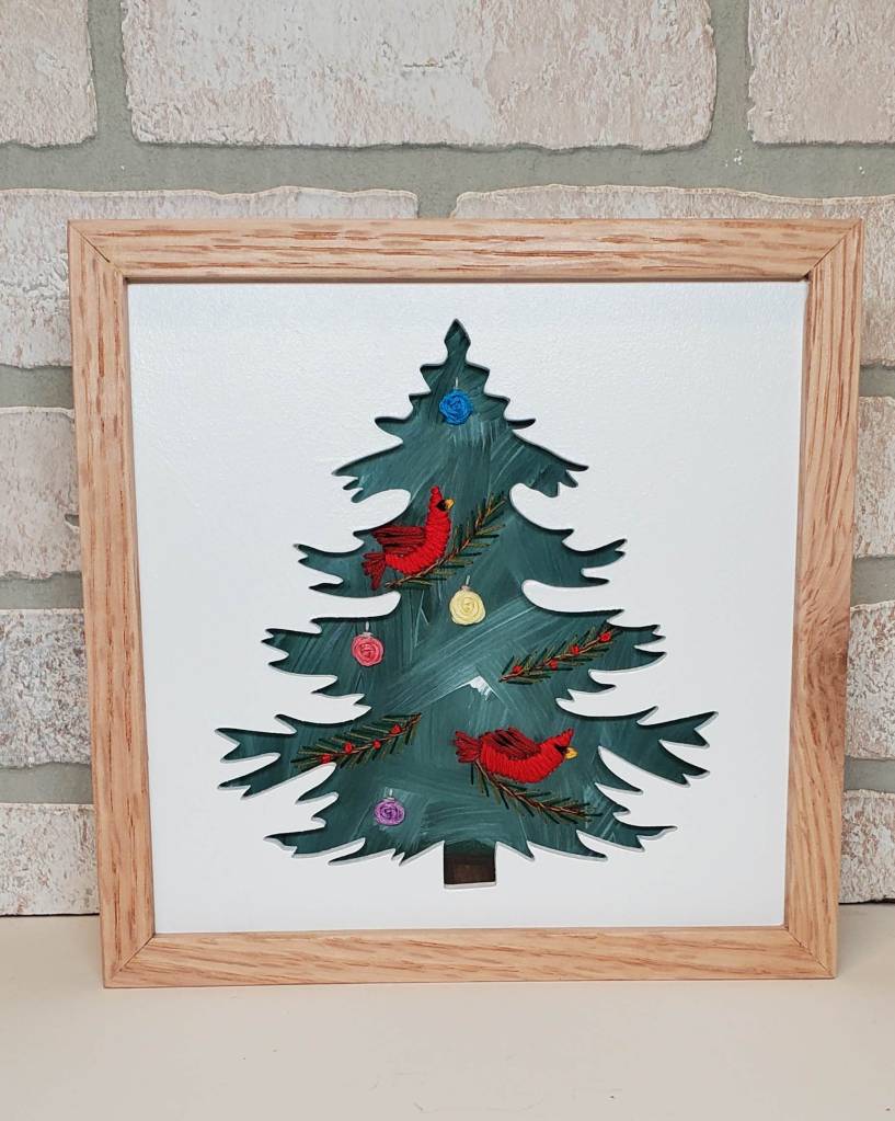 Evergreen tree silhouette with green background and embroidered cardinal and ornament details.