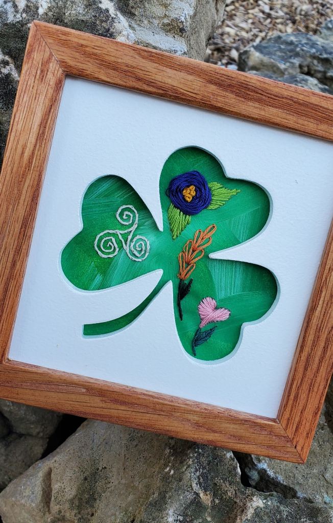Shamrock silhouette with green background and embroidered floral designs.