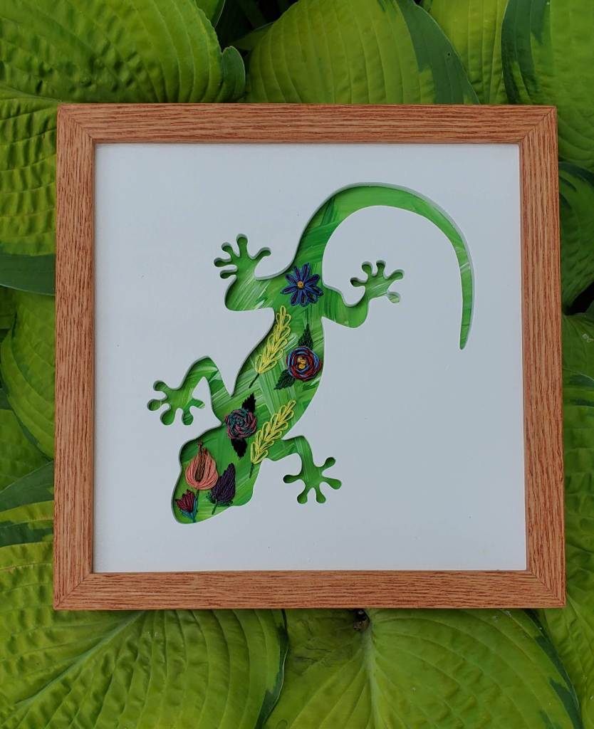 Gecko silhouette with bright green background and embroidered flower designs.