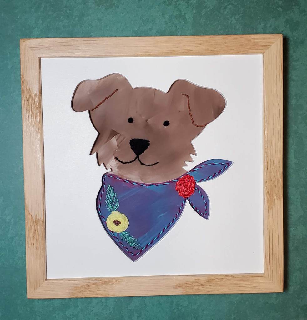 Floppy eared dog face silhouette. Brown down with blue bandana, embroidered flower details.
