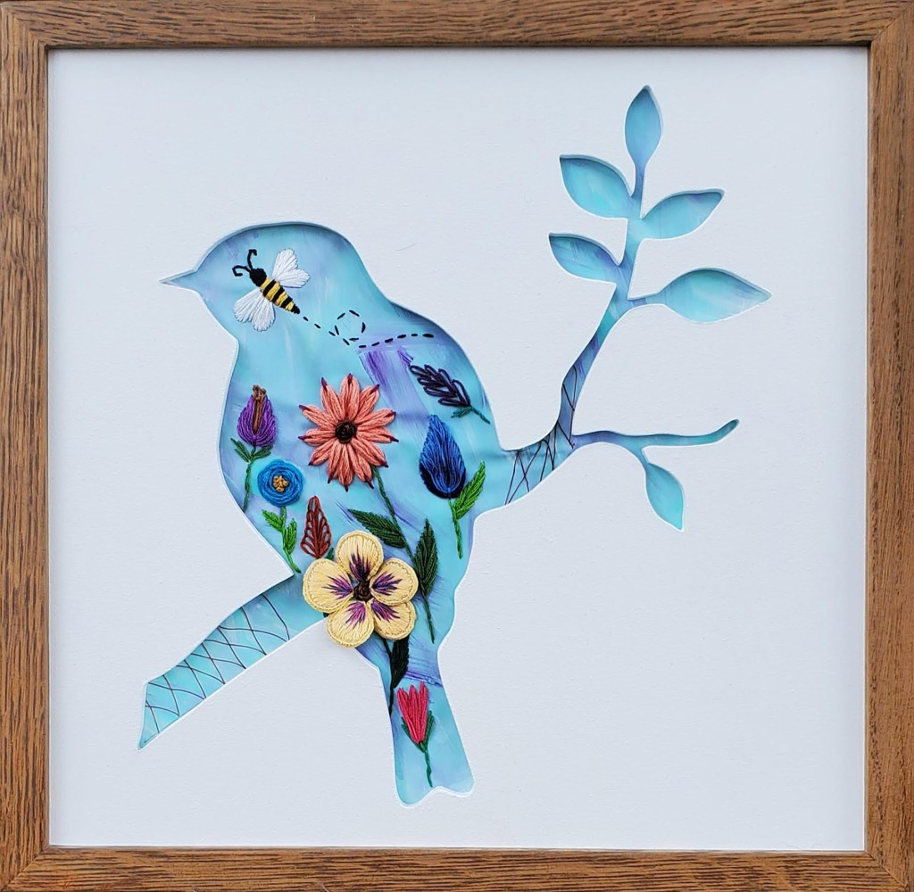 Bird on a branch silhouette with blue background and embroidered flowers and bee details