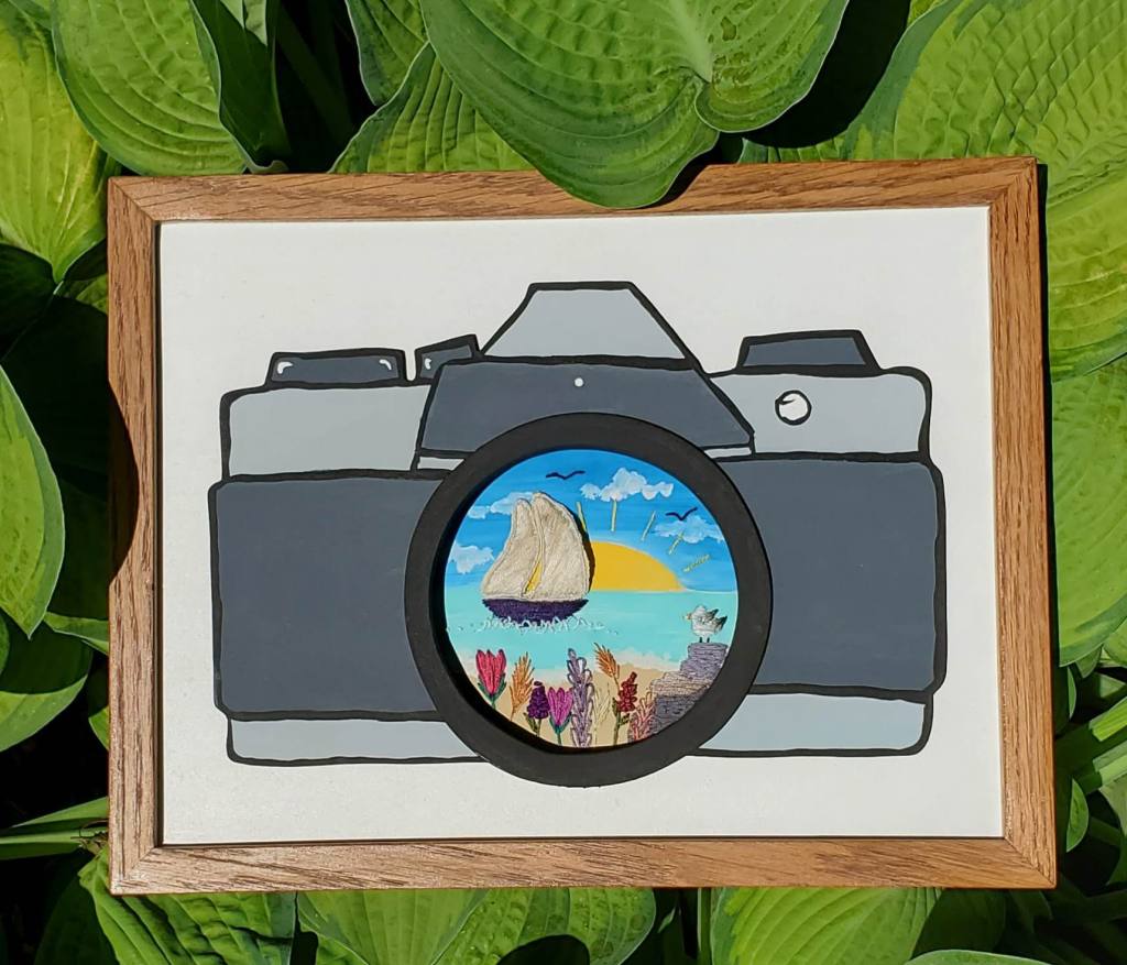 Vintage looking camera with a sun and beach background with an embroidered sailboat, seagull and flower details.
