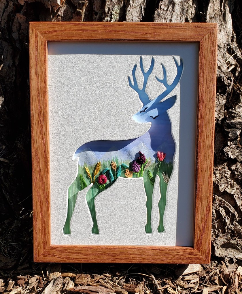 Side view of a deer silhouette with pastel sky background and embroidered flower details.