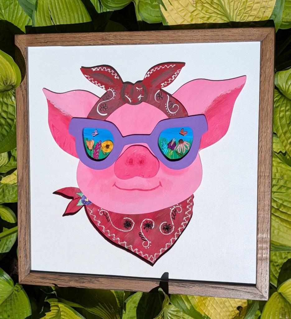 Face of a pig wearing a bandana and sunglasses. Embroidered flower details in the sunglasses.