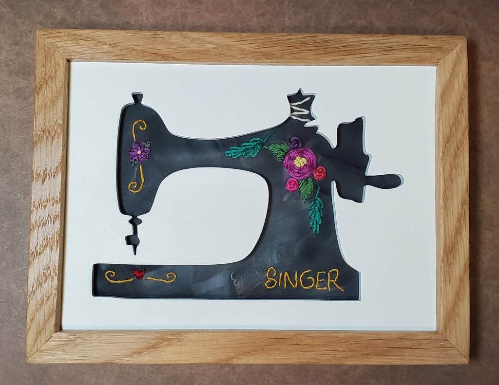 Singer sewing machine silhouette with black background and embroidered floral designs