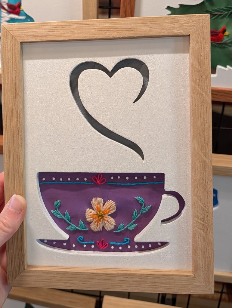 Tea cup silhouette with heart shape steam, purple background with embroidered flowers and geometric pattern details
